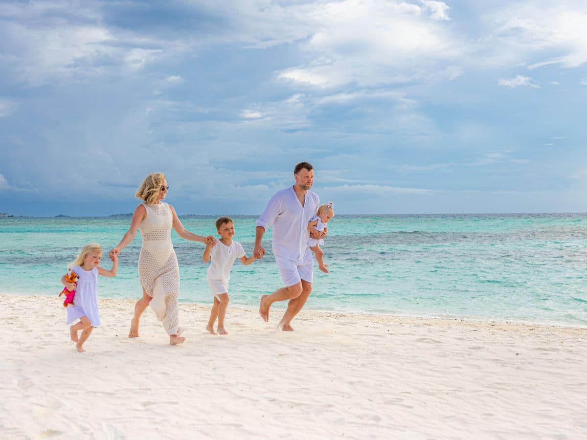 A joyful family strolls along a tropical beach, enjoying a sunny day together., Grecia — CautaVacanta.ro